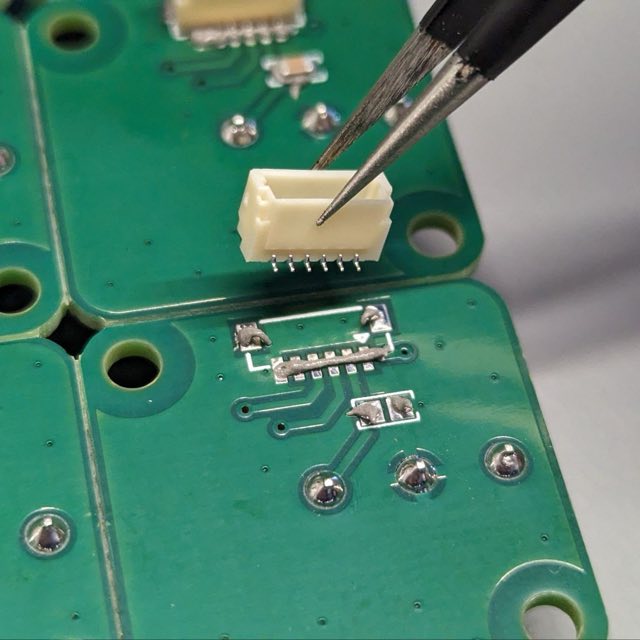 A through-hole connector being placed with tweezers