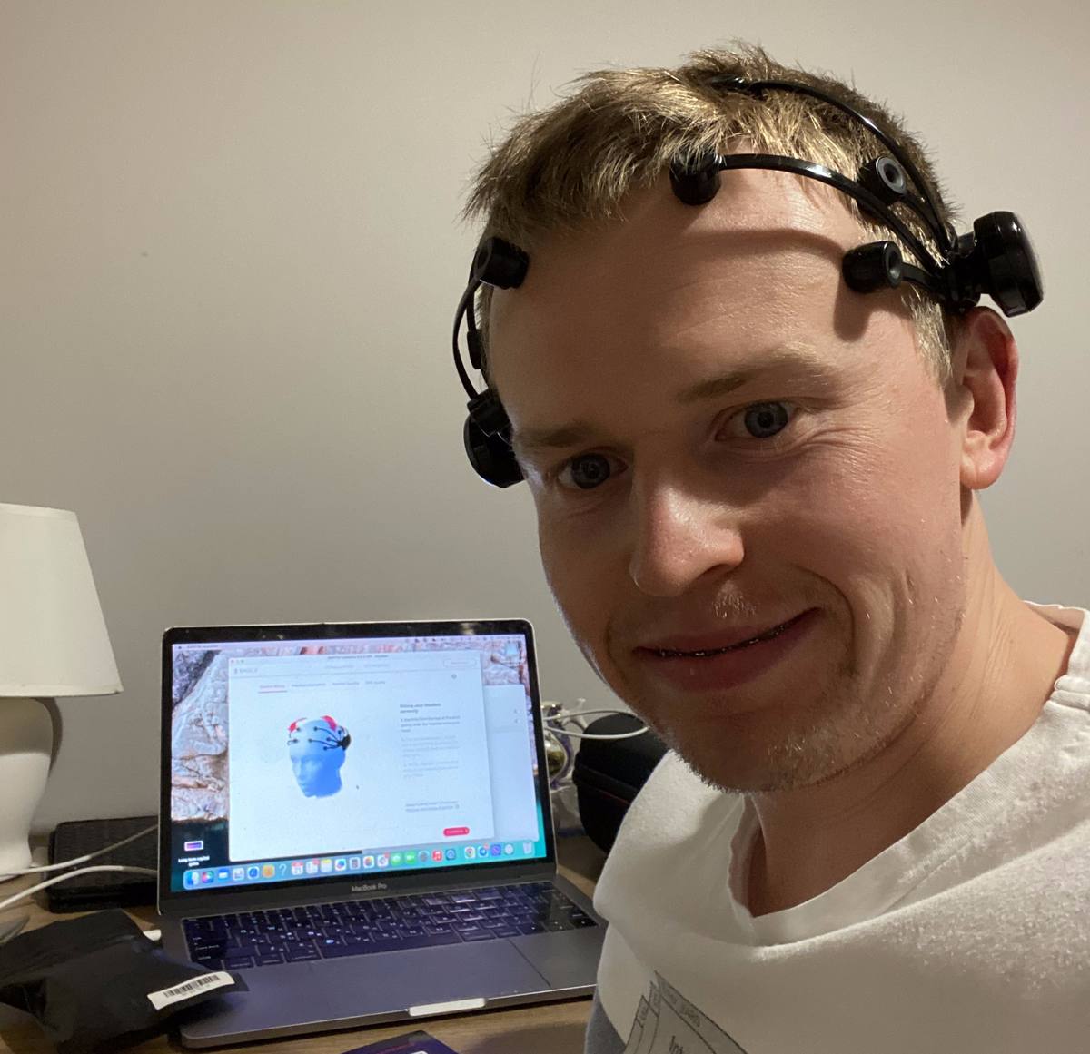 A Fluvius R&D session: an EMOTIV brain-computer interface headset fitted over the hair, sensors pressed to the scalp, with the sensor contact-quality screen open on the laptop on the desk alongside
