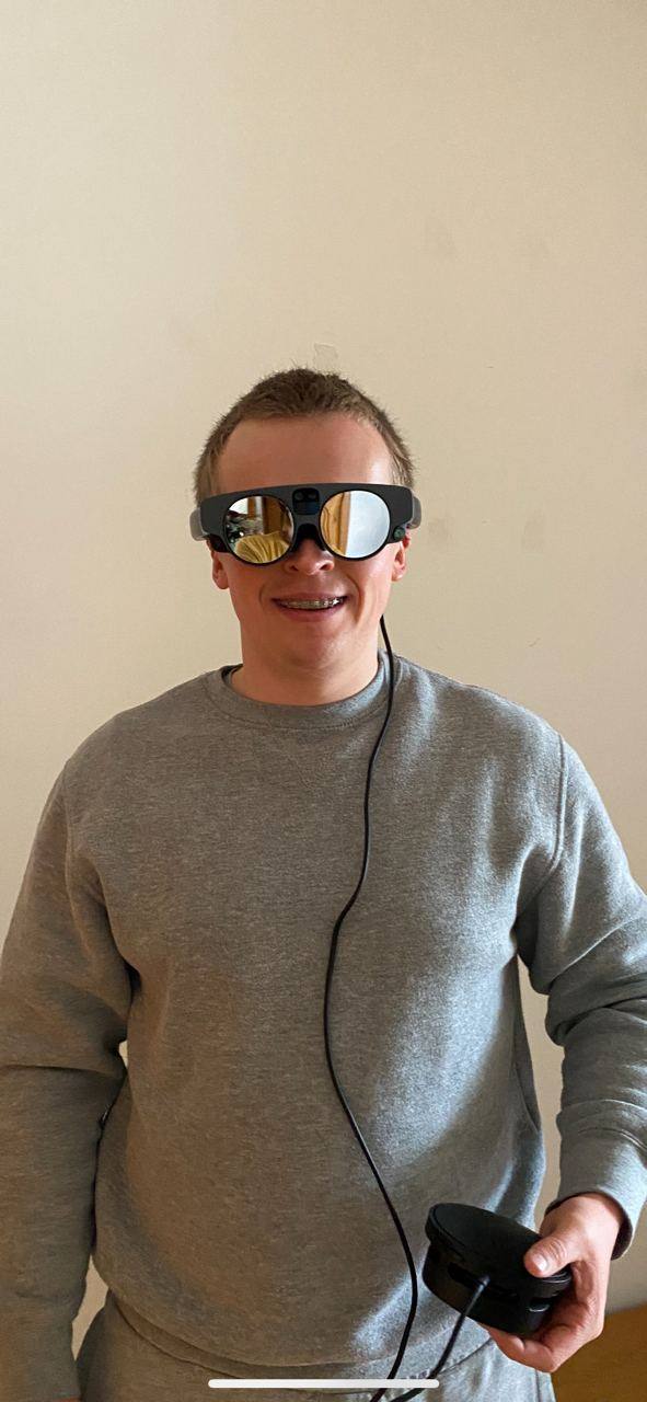 A Fluvius R&D session: a person wearing Magic Leap 3 AR glasses in an ordinary room, arms down, holding the tethered compute unit in one hand